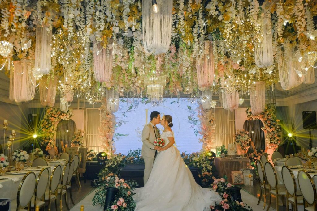 Romantic wedding setup in Davao City with a bride and groom under a luxurious floral ceiling, chandeliers, and elegant reception styling by a wedding planner and event organizer.